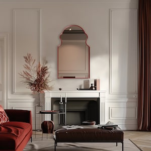 Bohemian Arched Mirror with red frame finish hang on the wall of a living room over a fireplace.