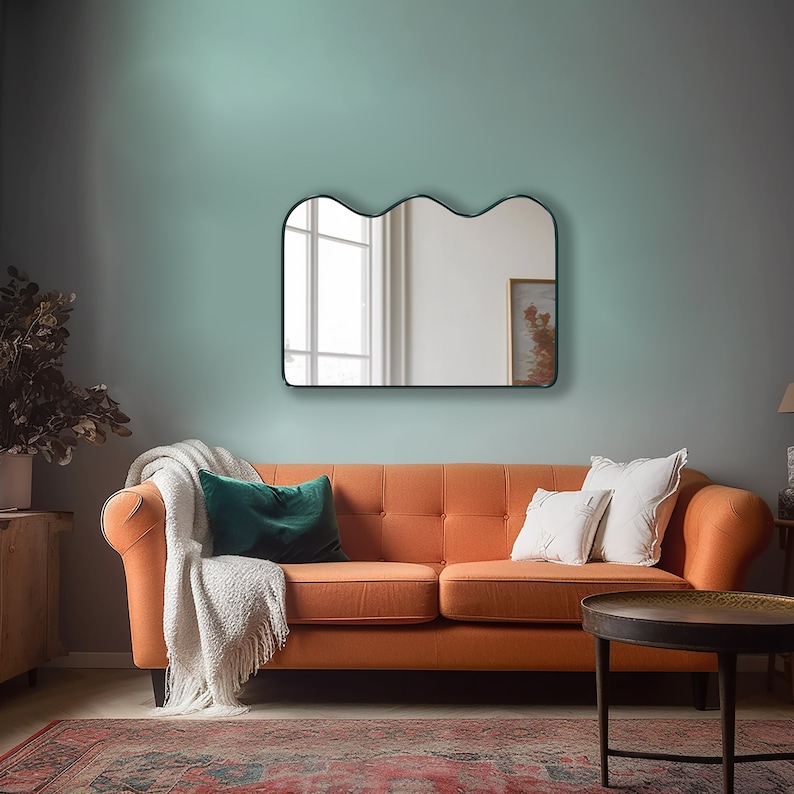 Squiggle mirror with emerald frame hung on the wall of a living room.