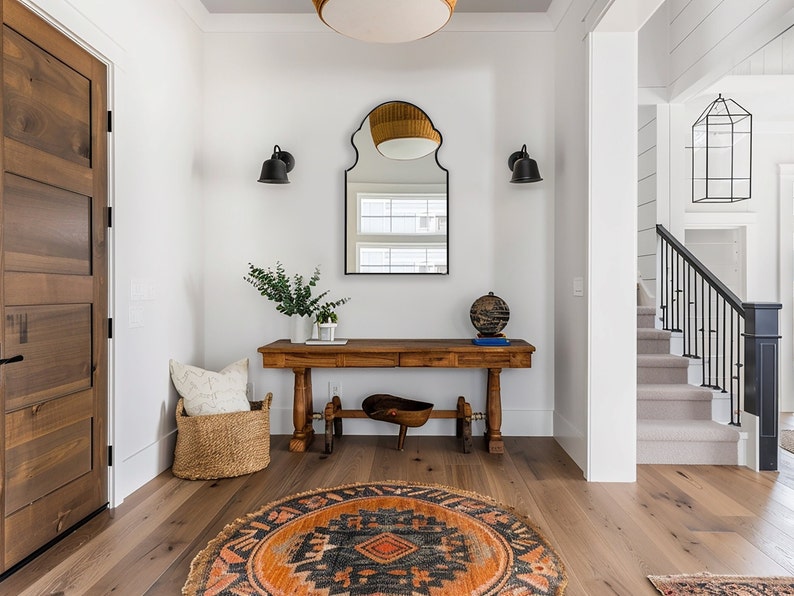 Bohemian Arched Mirror with black frame finish hang on the wall of an entryway over a wooden console.