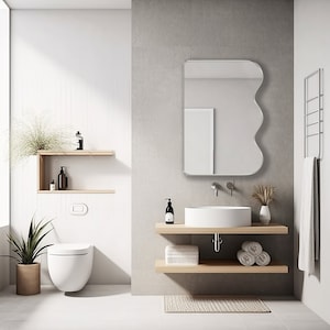 Squiggle mirror with silver frame hung on the wall of a bathroom.