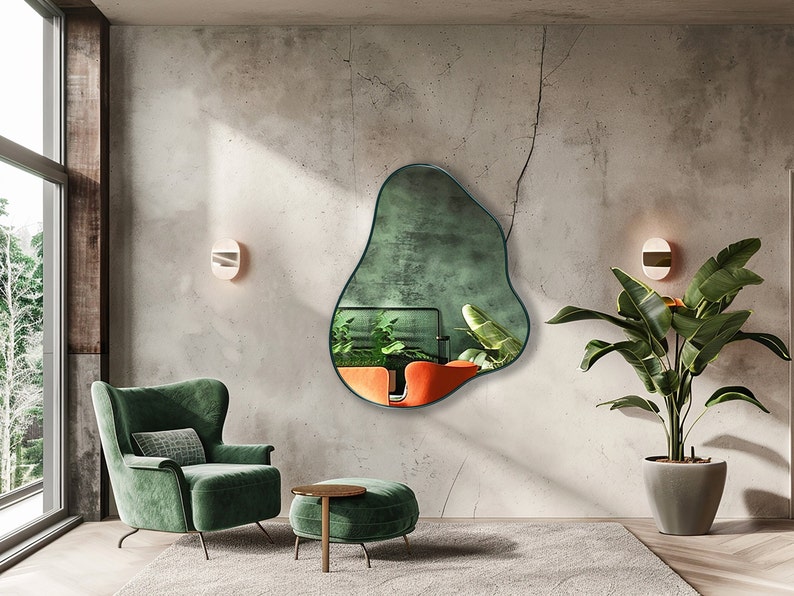 Organic Pebble Mirror with emerald frame finish hung on the wall of a living room, over an armchair.