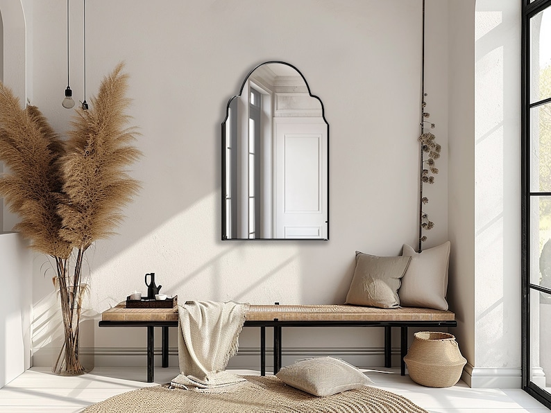 Arched Moroccan Mirror with black frame finish hung on the wall of an entryway over a bench.