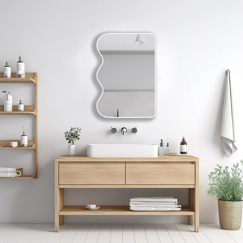 Squiggle mirror with white frame hung on the wall of a powder room.