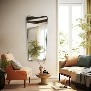 Italian butterfly mirror with emerald frame hung on the wall of a living room next to the couch and armchair.