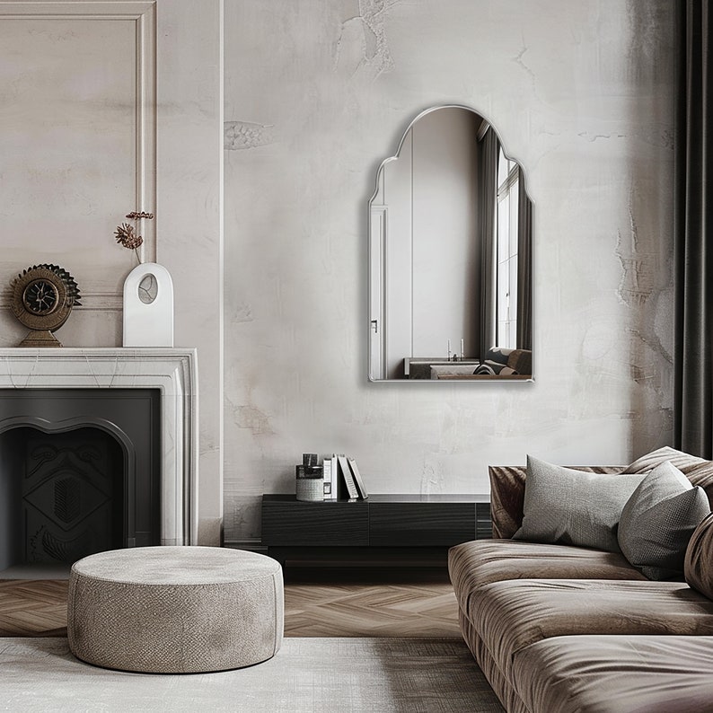 Arched Moroccan Mirror with silver frame finish hung on the wall of a living room over a console.