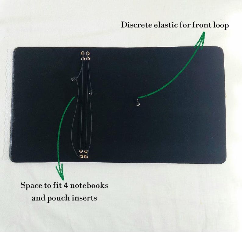 May include: A black rectangular notebook cover featuring an internal system of thin black elastic cords secured by metal eyelets. The interior includes a discrete elastic for a front loop and space to fit 4 notebooks and pouch inserts.
