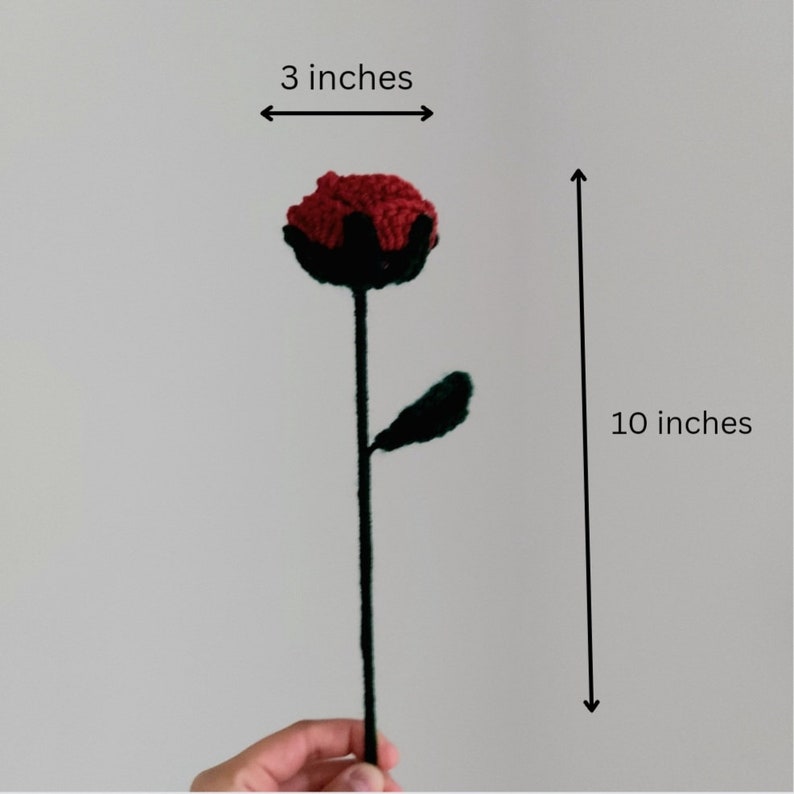 Puede incluir: Una flor de ganchillo hecha a mano con una flor roja, base negra y hoja verde. La flor mide 25 cm de largo, con la flor que mide 7,6 cm de ancho. El tallo es verde oscuro.