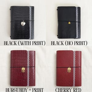 May include: Four rectangular journals featuring a vertical white lace trim and a central elastic band with a metal charm. The top left is black with a crocodile print, top right is smooth black, bottom left is burgundy crocodile, and bottom right is cherry red.
