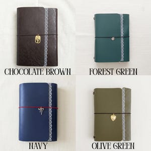 May include: Four rectangular journals in chocolate brown, forest green, navy, and olive green. Each journal features a vertical white lace trim, a horizontal elastic closure band, and a small metal charm including a rose, heart, or bow.