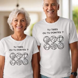 Peut inclure: Deux personnes portant des t-shirts blancs avec l'inscription "TU TIRES OU TU POINTES ?" et un graphisme de six boules stylisées. Les t-shirts sont à manches courtes, le texte et le graphisme sont noirs.