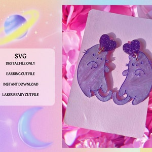 Könnte beinhalten: Lilafarbene Ohrringe in Katzenform mit Glitzerherzen. Die Ohrringe befinden sich auf einer weißen Karte mit dem Text "SVG DIGITAL FILE ONLY EARRING CUT FILE INSTANT DOWNLOAD LASER READY CUT FILE".
