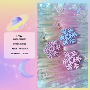 May include: A pair of snowflake earrings with a light blue and pink iridescent finish. The earrings are made of acrylic and have a simple, elegant design. The text "SVG DIGITAL FILE ONLY EARRING CUT FILE INSTANT DOWNLOAD LASER READY CUT FILE" is visible in the image.