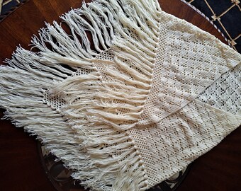 May include: A white crocheted shawl with a fringe border. The shawl has a delicate openwork pattern.