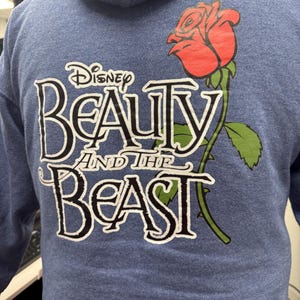 May include: Blue hooded sweatshirt with a white graphic of a red rose and the text "Disney Beauty and the Beast".