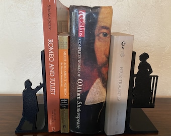 Peut inclure: Ensemble de serre-livres en métal noir avec des silhouettes de personnages de Shakespeare. Ils maintiennent des livres, dont "Roméo et Juliette" et "Quatre Tragédies". Les livres sont de couleurs variées, notamment rouge, orange et blanc.