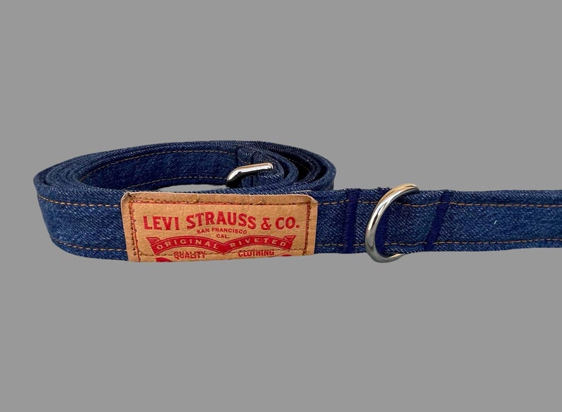 May include: A blue denim dog leash with a metal ring and a rectangular brown label. The label reads "LEVI STRAUSS & CO. SAN FRANCISCO CAL. ORIGINAL RIVETED CLOTHING QUALITY".