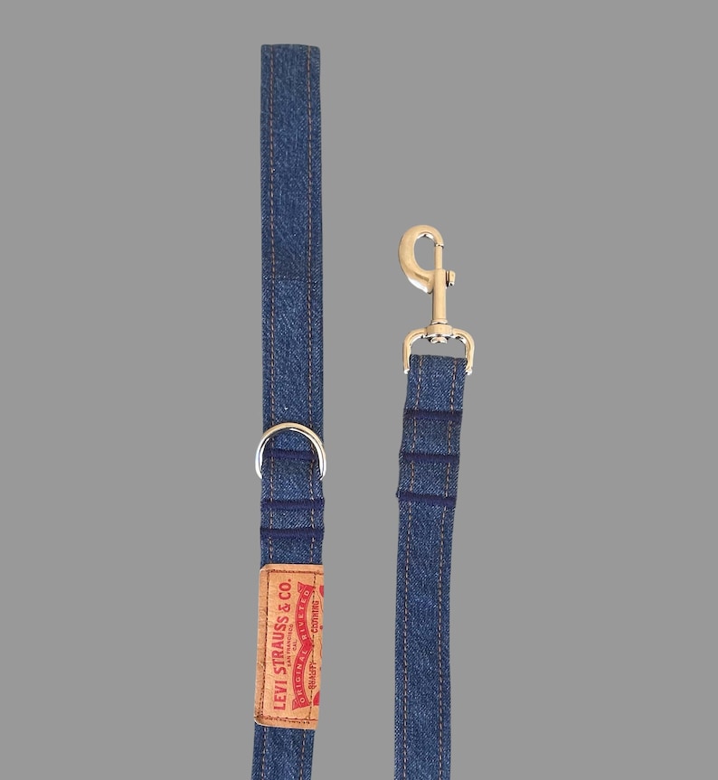 May include: A blue denim dog leash with a silver metal clasp and a D-ring. The leash features a brown leather tag with the "Levi Strauss & Co." logo in red and white.
