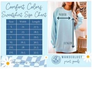 以下が含まれることがあります： 水色のComfort Colorsスウェットシャツとサイズチャート。サイズチャートは、Sから3XLまでのサイズで、幅53.3〜74.9cm、長さ69.9〜82.6cmの寸法をcmで表示しています。「Wanderlust print goods」の文字も表示されています。