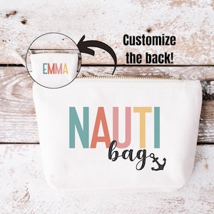 May include: A white canvas zippered pouch with the text "NAUTI bags" in colorful letters and a black anchor symbol. The pouch has a zipper closure and a personalized name on the back.