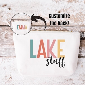 May include: White canvas cosmetic bag with a gold zipper and the words "LAKE stuff" in colorful block letters. The bag also features the text "Customize the back!" and a small circle with the name "EMMA".