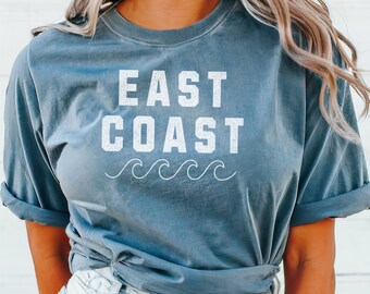 May include: A blue t-shirt with the text "EAST COAST" in white with a wavy line underneath. The shirt is tied at the waist.