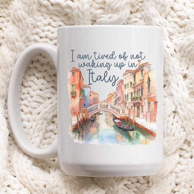 May include: White ceramic coffee mug with a watercolor image of a canal in Venice, Italy. The text "I am tired of not waking up in Italy" is printed on the mug.