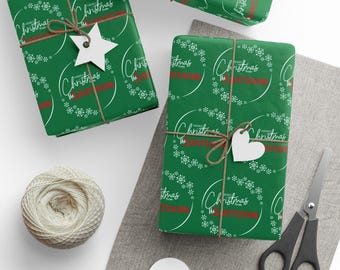 Puede incluir: Papel de regalo verde con motivos de copos de nieve y texto blancos. Los regalos están atados con hilo y adornados con etiquetas blancas en forma de estrella y corazón. También hay un carrete de hilo, tijeras y etiquetas en blanco.