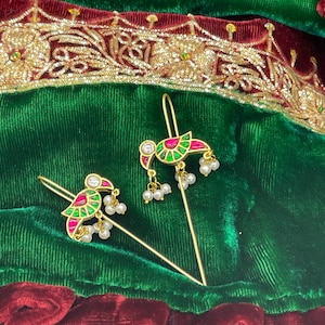 May include: Two gold hair pins with green, red, and white enamel bird designs and pearl accents.