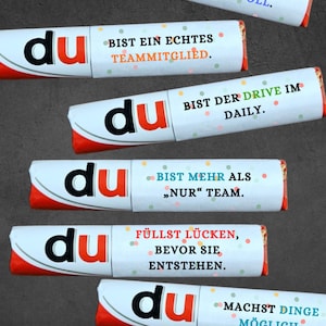 May include: A collection of six candy bar wrappers with the word "du" in a bold font. Each wrapper has a different message in German, such as "You are reliable & valuable" and "You make things possible."