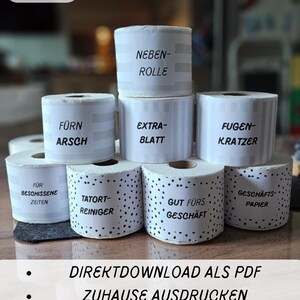 May include: A stack of white paper rolls with various German phrases printed on them, including "NEBEN-ROLLE" and "EXTRA-BLATT". The image also includes the text "PDF - DRUCKVORLAGE" and bullet points with German text.