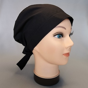 May include: Black scrub hat with a tie at the back. The hat is made of a soft, stretchy fabric.