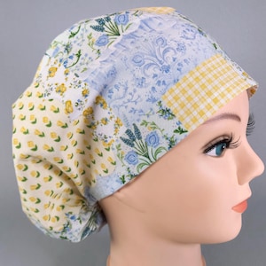 May include: A patchwork scrub cap with floral, gingham, and damask patterns in yellow, blue, and white. The cap is designed for comfort and is made of soft fabric.