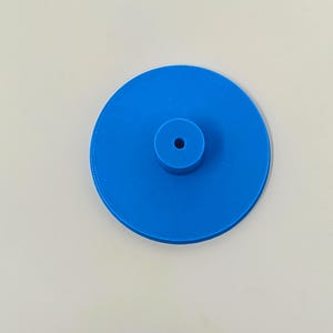 May include: A blue plastic disc with a small hole in the center.