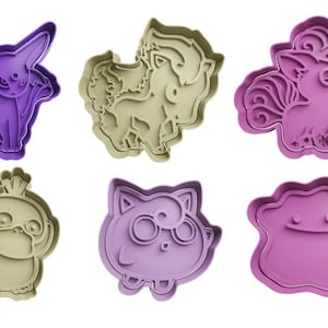 May include: Six different cookie cutters, each featuring a different cartoon character. The cutters are made of purple and beige plastic. The characters include a unicorn, a cat, a bird, a dog, and two other creatures.