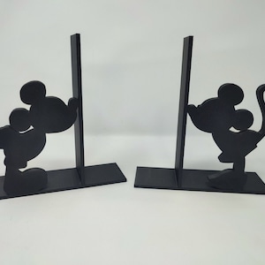 Op de afbeelding: Zwarte houten boekenleggers in de vorm van Mickey Mouse-silhouetten. De boekenleggers staan op een wit oppervlak.