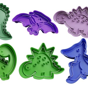 Könnte beinhalten: Satz mit sechs Dinosaurier-Ausstechern, mit verschiedenen Dinosauriern in Grün, Lila und Blau. Die Ausstecher sind aus Kunststoff und perfekt zum Ausstechen von Dinosaurier-förmigen Keksen.
