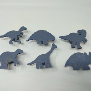 Könnte beinhalten: Sechs blaue Dinosaurierformen aus Schaumstoff. Die Dinosaurier sind ein Stegosaurus, ein Brachiosaurus, ein Triceratops, ein Velociraptor und zwei weitere Dinosaurier.