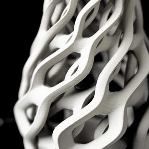 May include: A white, abstract sculpture with a complex, interwoven design. The form appears to be a vase or decorative object, featuring a series of curved, flowing lines that create open spaces. The piece is set against a black background, highlighting its intricate structure.