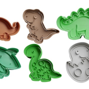 Peut inclure: Ensemble de six emporte-pièces en forme de dinosaure. Les emporte-pièces sont en plastique vert, marron et gris. Les dinosaures comprennent un tricératops, un stégosaure, un ptérodactyle, un brachiosaure, un tyrannosaure rex et un bébé dinosaure éclosant d'un œuf.