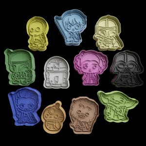 May include: A selection of plastic cookie cutters in various colours, depicting characters from a popular science fiction franchise. The cutters are in shades of yellow, blue, green, brown, pink, and black, with detailed designs of iconic characters.
