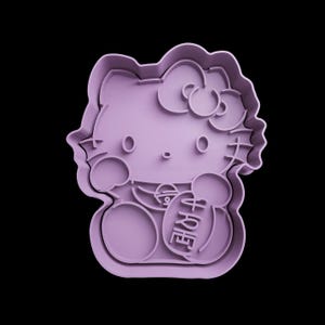 May include: Purple plastic cookie cutter shaped like Hello Kitty holding a gift. The gift has the word "Happy" written on it.