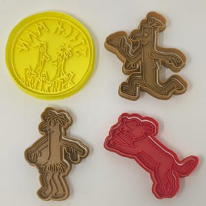 May include: A set of four cookie cutters featuring characters from the children's book "Where the Wild Things Are". The cutters are made of brown and red plastic and include a yellow cutter with the book's title.