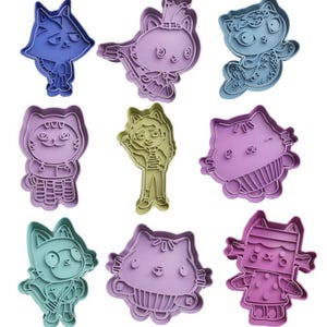 May include: Nine colourful cookie cutters shaped like cartoon characters. The characters include a cat wearing a crown, a cat wearing a flower crown, a cat wearing a plaid shirt, a girl with long hair, a cat with a striped shirt, a cat with a bow, a cat with a bandana, a cat with a striped shirt, and a cat with a polka dot dress.