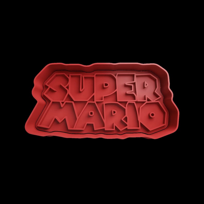 Puede incluir: Cortador de galletas de pl&aacute;stico rojo con forma del logotipo de Super Mario. El logotipo est&aacute; en una fuente en negrita y en bloques.