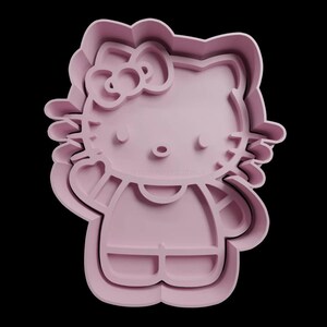 May include: Pink plastic cookie cutter shaped like Hello Kitty. The cutter has a bow, a face with whiskers, and a simple dress.