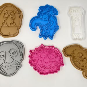 Könnte beinhalten: Sechs Ausstecher in verschiedenen Farben und Formen, die Figuren aus der Sesamstraße zeigen. Die Ausstecher sind aus Kunststoff und zum Ausstechen von Keksen in Form von Big Bird, Cookie Monster, Elmo, Bert, Ernie und Oscar the Grouch.