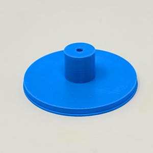May include: A blue plastic base with a small hole in the center and a raised cylinder in the middle.