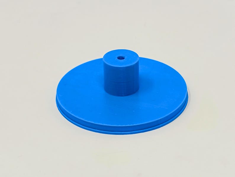 May include: A blue plastic base with a small hole in the center and a raised cylinder in the middle.