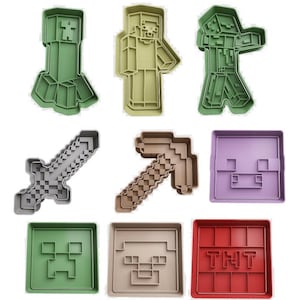 Könnte beinhalten: Eine Sammlung von Ausstechformen aus Kunststoff in verschiedenen Formen und Farben. Das Set enthält Charakter- und Gegenstandsdesigns aus einem beliebten Videospiel, wie z. B. ein Schwert, eine Spitzhacke und ein TNT-Block. Die Ausstecher sind in Grün-, Beige-, Grau-, Braun-, Lila- und Rottönen gehalten.