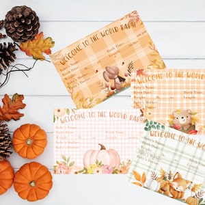 May include: Four baby announcement cards with the text "WELCOME TO THE WORLD BABY!" in various plaid and floral designs. The cards feature illustrations of a bear, fox, and pumpkin, with space to record baby's details. Autumn leaves and pumpkins decorate the scene.